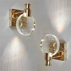 Two gold wall sconces with glass shades on a light gray background