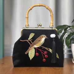 A close-up of an embroidered crossbody bag, showcasing the intricate bird design and fringe detailing .