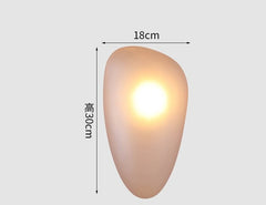 Golden Atelier LED wall lights in a modern glass pebble design, mounted on a wall and casting a warm glow. Smoky Amber