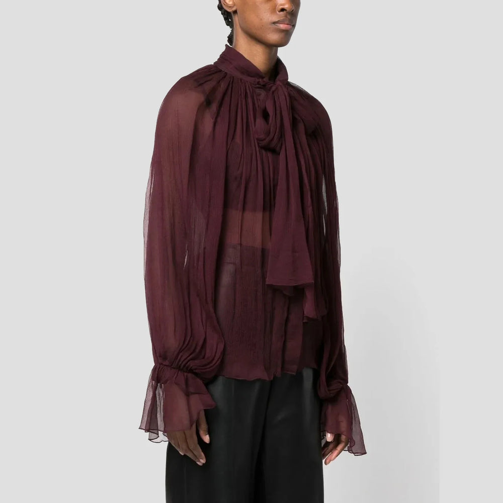 Person wearing a burgundy sheer blouse with a plain background