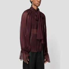 Person wearing a burgundy sheer blouse with a plain background