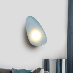 Golden Atelier LED wall lights in a modern glass pebble design, mounted on a wall and casting a warm glow. Smoky Blue