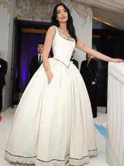 Woman in a white dress with black details standing indoors.