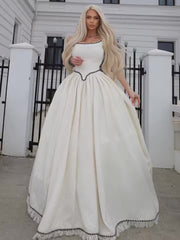 Woman in a white dress with black trim standing in front of a building.