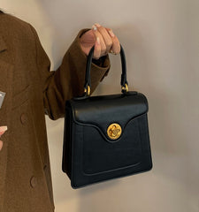 Black structured top handle bag with gold hardware