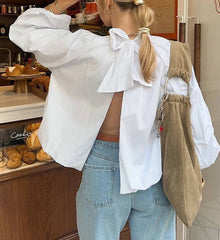 Person wearing a white blouse with ruffled sleeves and light blue jeans in a bakery setting.
