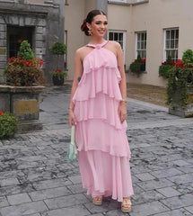 Woman in a pink dress standing in an outdoor setting with decorative plants and flowers.