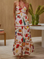Woman wearing a colorful dress with food print in a room with a wooden wall and table.