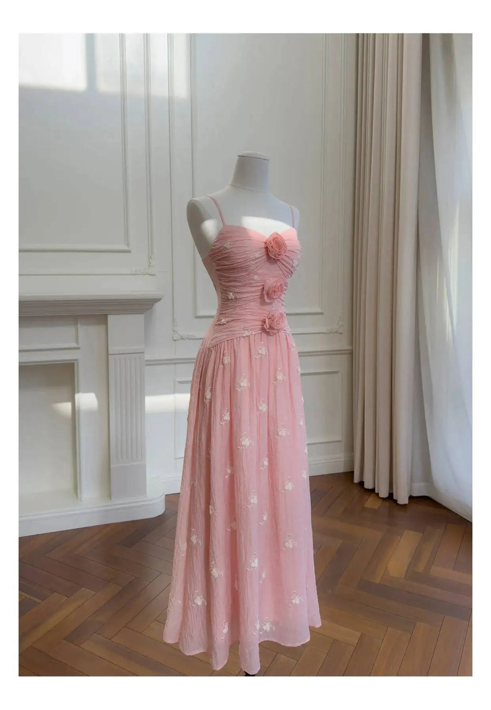 Pink embroidered midi dress with rose embellishments on a mannequin