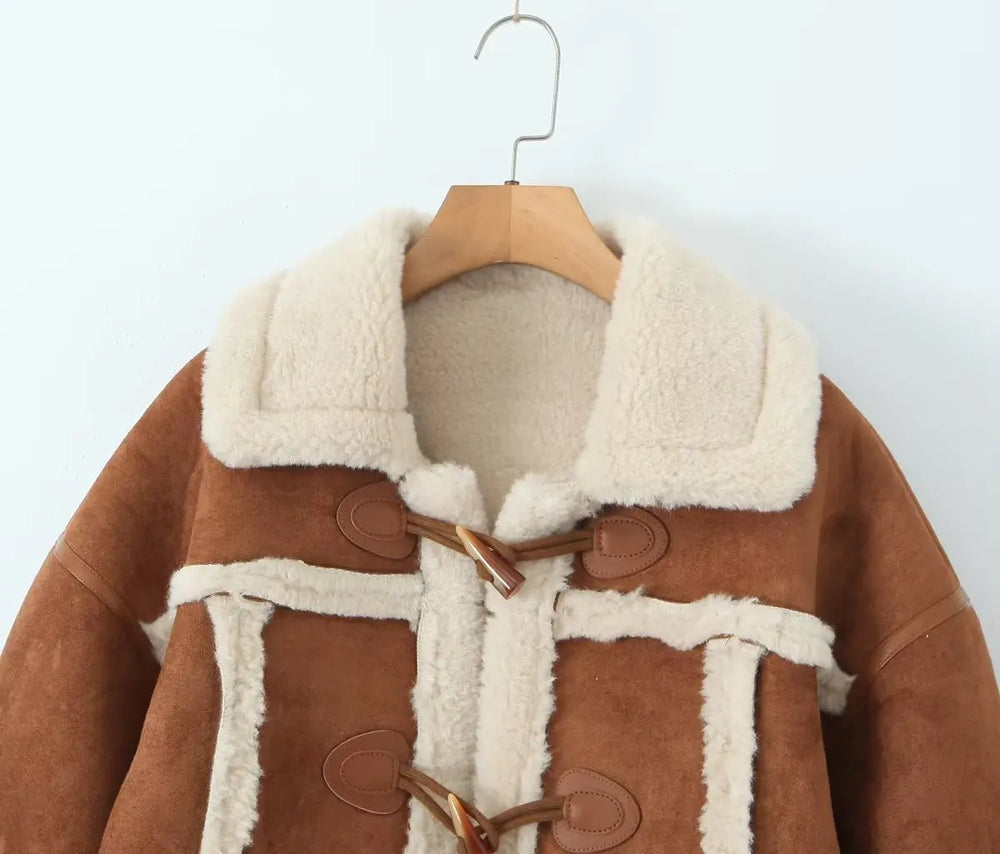 Brown coat with white fur lining on a wooden hanger against a light background