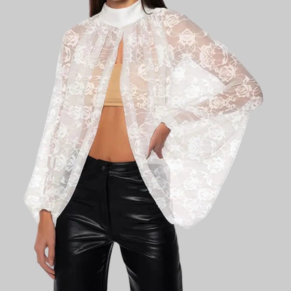 White lace cover-up over a beige top and black pants on a white background