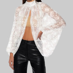 White lace cover-up over a beige top and black pants on a white background