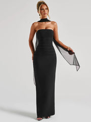 Model in strapless black ankle-length sheath dress with chiffon scarf and backless design.