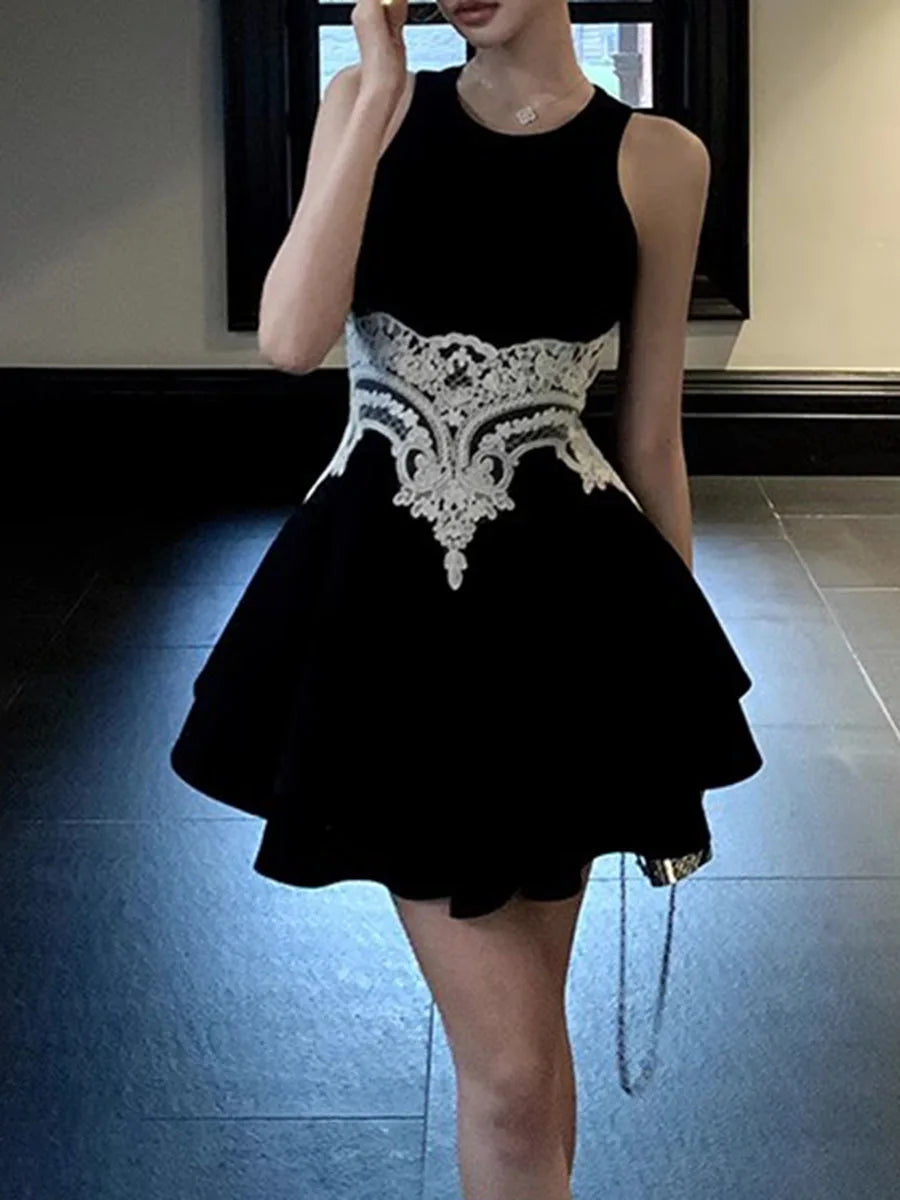 Black dress with white lace details worn by a person, standing indoors.