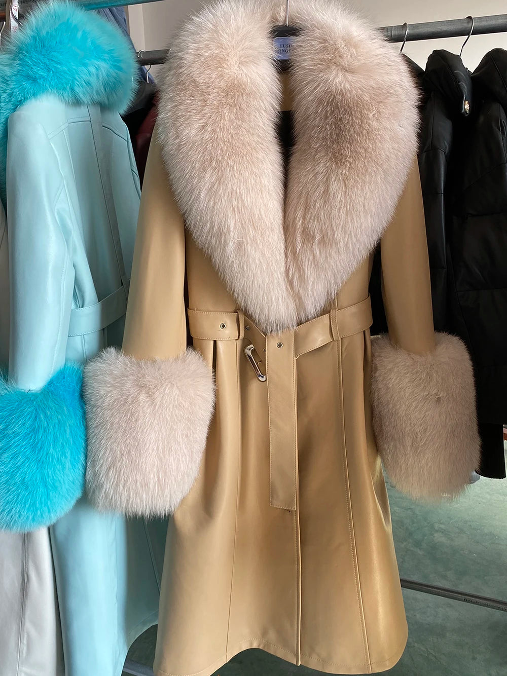 Beige coat with fur collar and cuffs on a rack