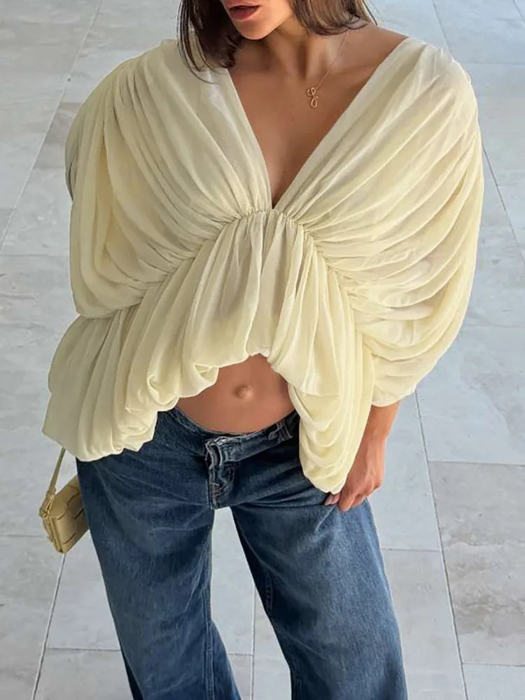 Model wearing a sheer ruched blouse with deep V-neckline