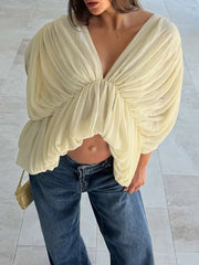 Model wearing a sheer ruched blouse with deep V-neckline