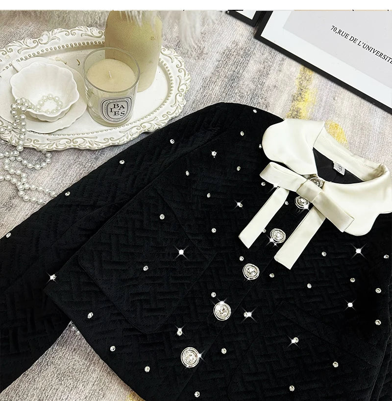 Black dress with white buttons and a white shoe on a textured surface with a candle and decorative items.