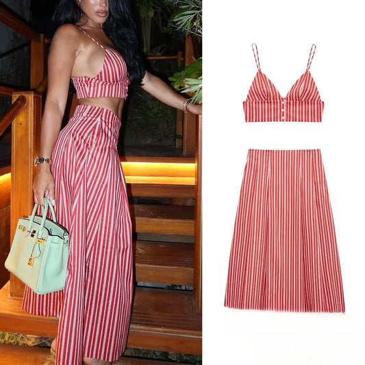 Woman wearing a red and white striped print two-piece set with a V-neck crop top and maxi skirt, holding a light green handbag.