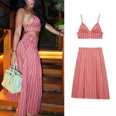 Woman wearing a red and white striped print two-piece set with a V-neck crop top and maxi skirt, holding a light green handbag.