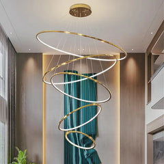 Modern spiral chandelier hanging in a room with a window and plant.