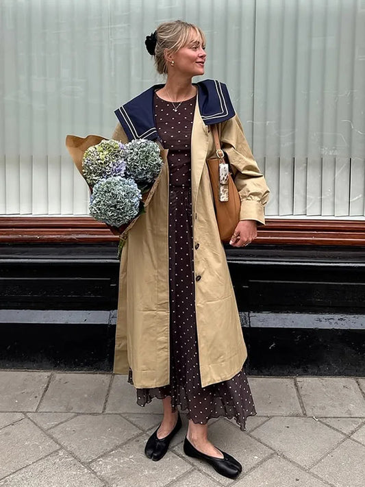 Woman wearing a trench coat with navy sailor collar and polka dot dress