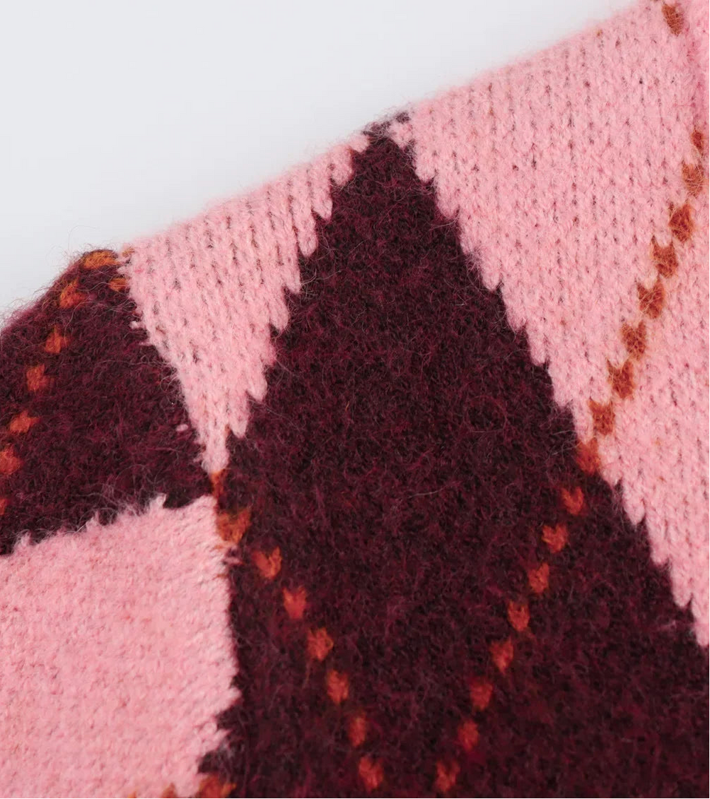 Close-up of a pink and maroon knitted fabric with a geometric pattern on a white background.
