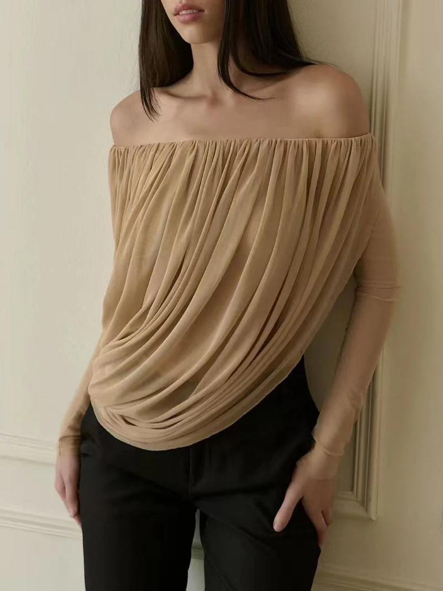 Woman wearing a beige off-shoulder top against a neutral wall
