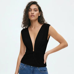 Woman wearing a black sleeveless top with a deep neckline on a white background
