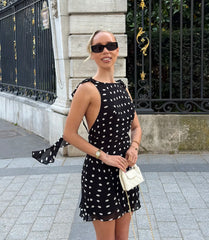 Front view of black polka dot mini dress with open back