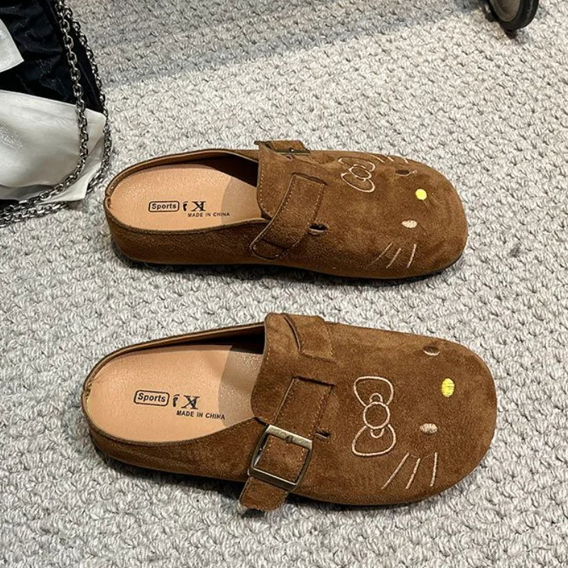 Brown suede Hello Kitty buckle mules on carpet