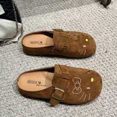 Brown suede Hello Kitty buckle mules on carpet