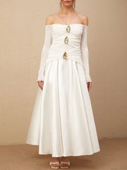 White off-shoulder dress with gold accents on a beige background