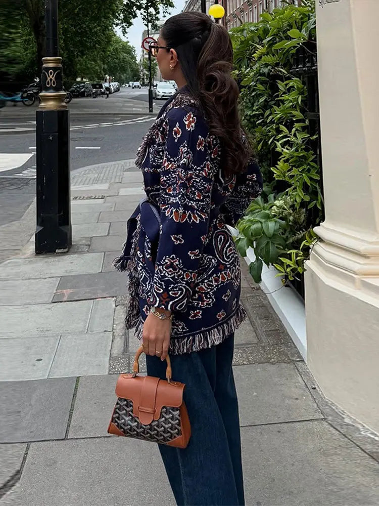 Woman in a floral dress with a brown handbag walking on a city street.