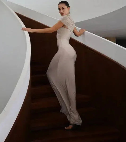 Woman in a long, light-colored dress standing on a spiral staircase.