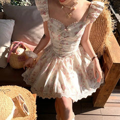 Woman in a floral dress sitting outdoors on a wooden bench.