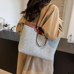 A woman carrying the denim tote bag over her shoulder, demonstrating its versatility and comfortable fit.