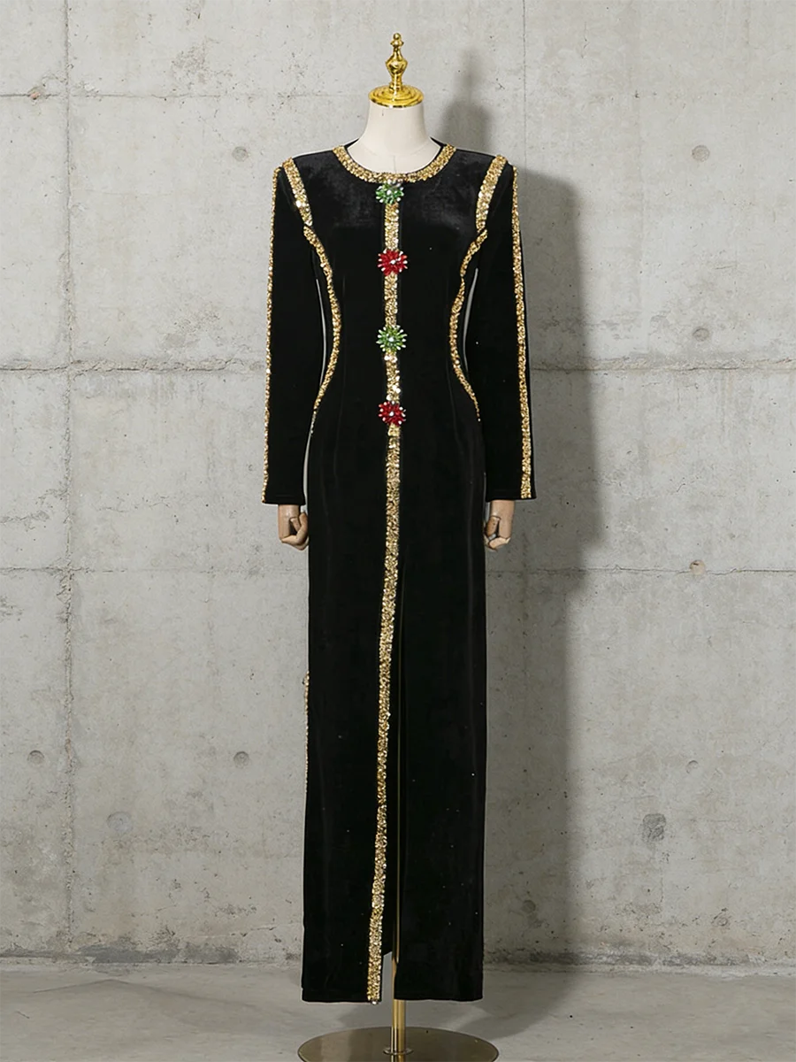 Black dress with gold and red embellishments on a mannequin against a concrete wall.