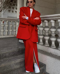 Person wearing a red suit standing on steps with a building in the background