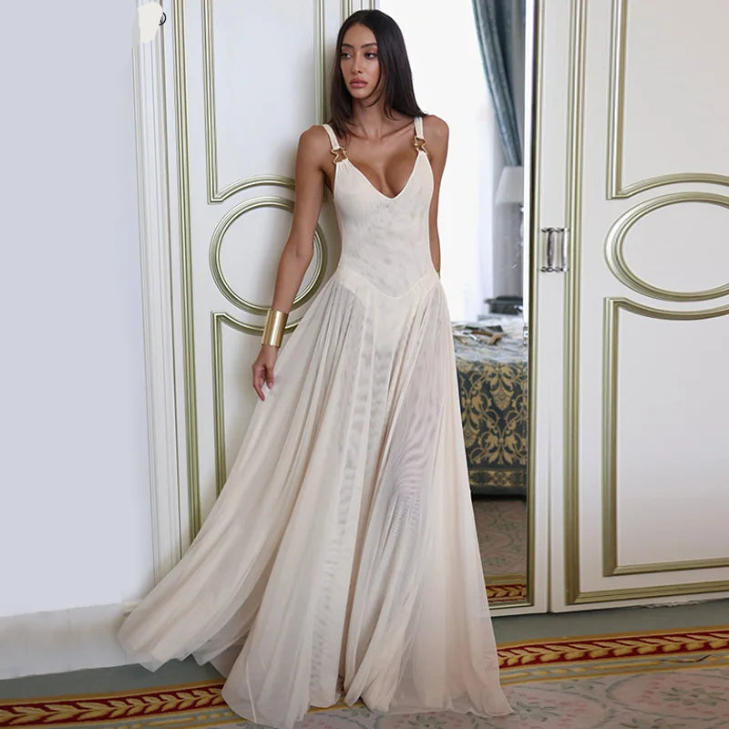 Woman in a white dress standing in an elegant room with decorative walls.