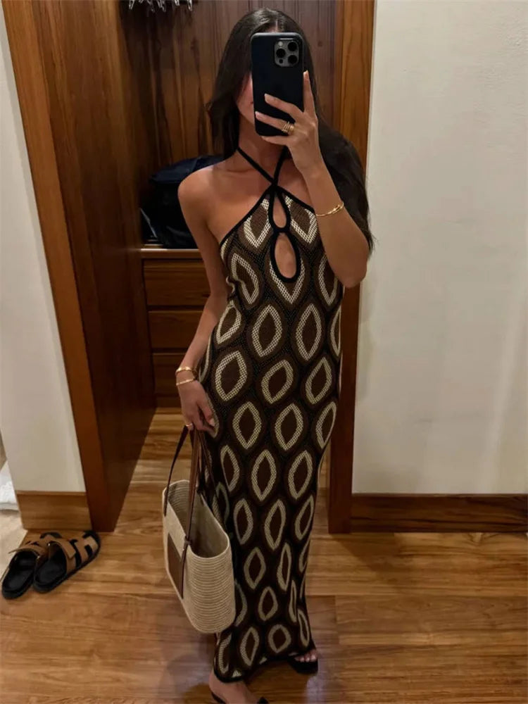 Woman taking a mirror selfie wearing a patterned dress in a room with wooden floor and white wall.
