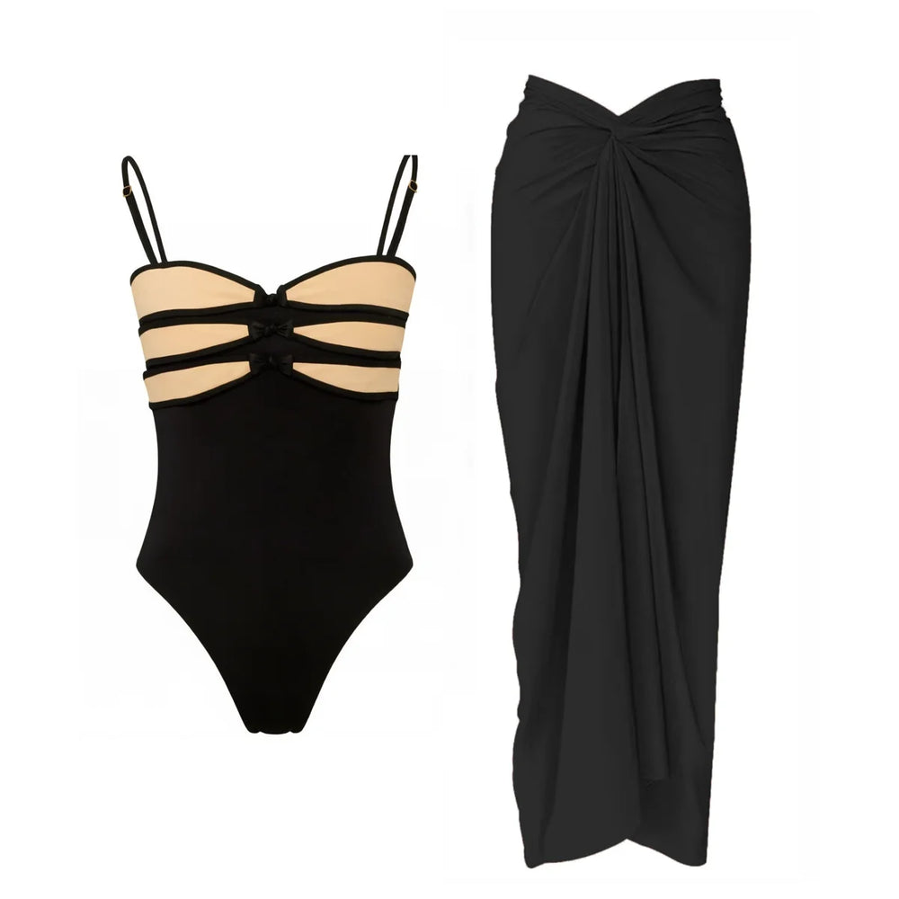 Black one-piece swimsuit with contrast trim and a draped black skirt.