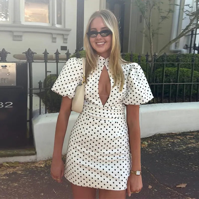 Woman wearing a polka dot dress with a deep neckline outdoors.