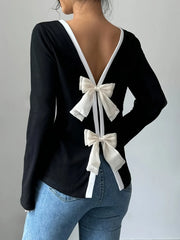 Black top with white bow details on a plain background