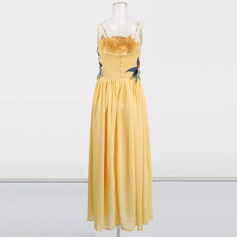 Yellow dress with floral straps on a mannequin against a white background
