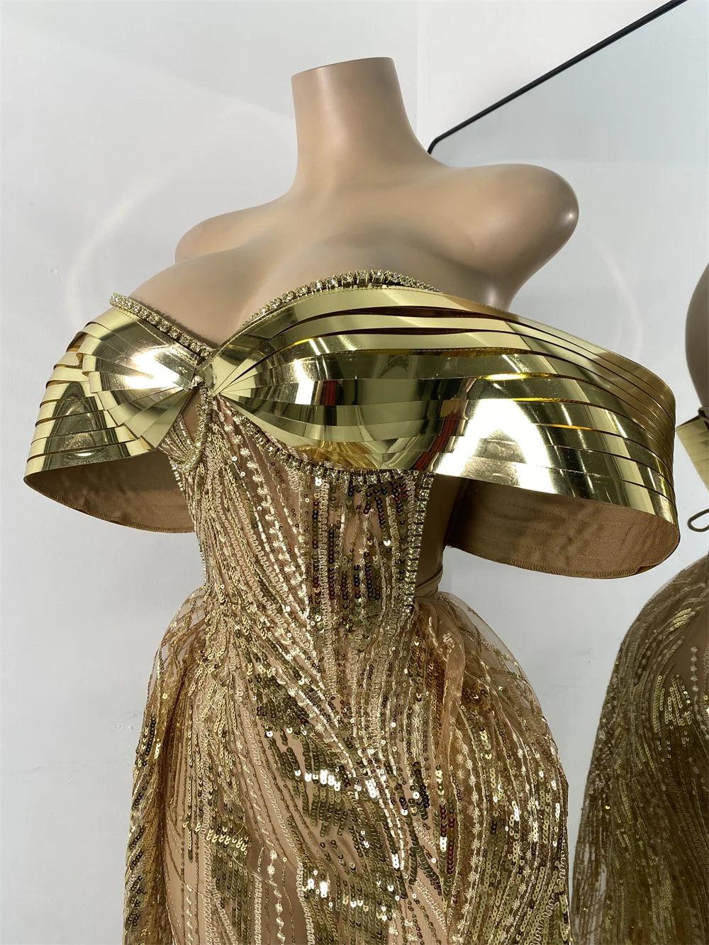 Gold sequin dress with gold headpiece on a mannequin against a white background