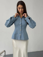Woman wearing a blue denim blouse against a plain background