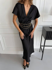 Woman wearing a black flutter sleeve satin maxi dress with a chain belt