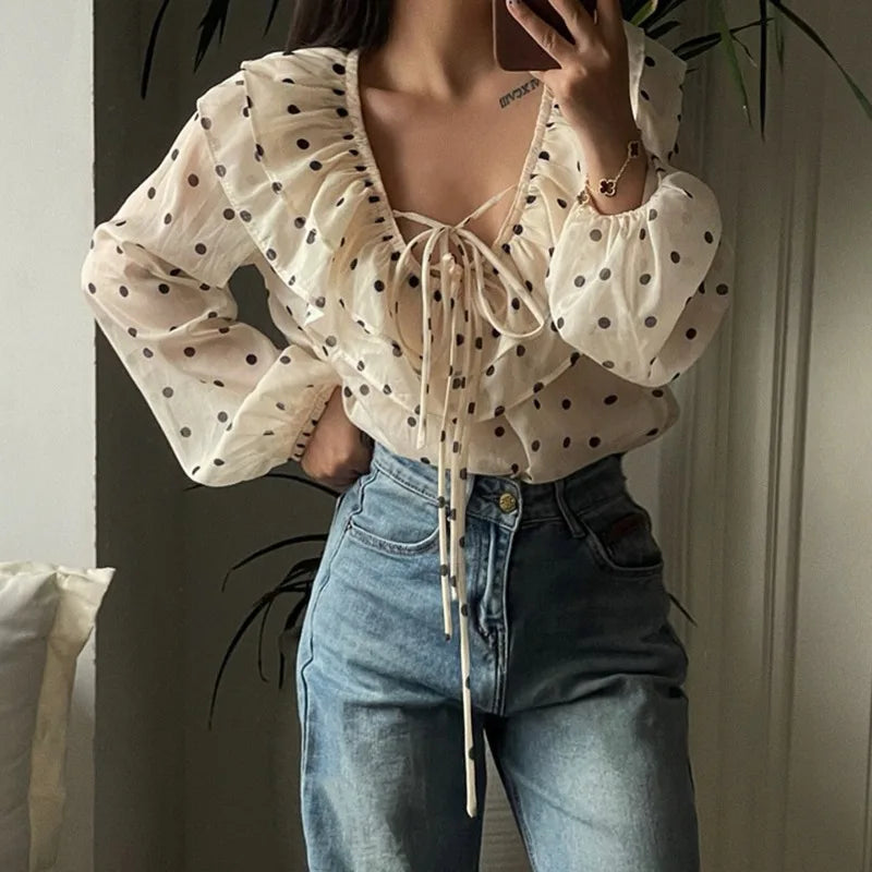 Person wearing a polka dot blouse and jeans indoors.