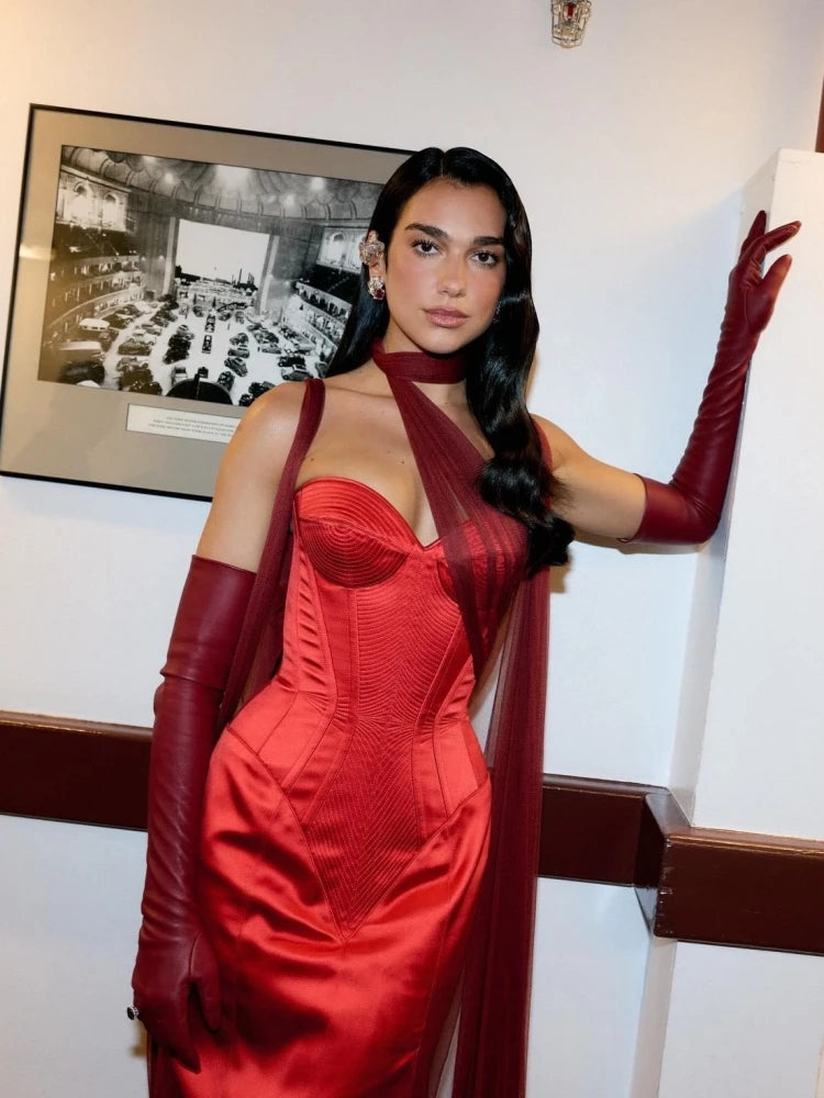 Woman in a red dress with long gloves posing indoors.